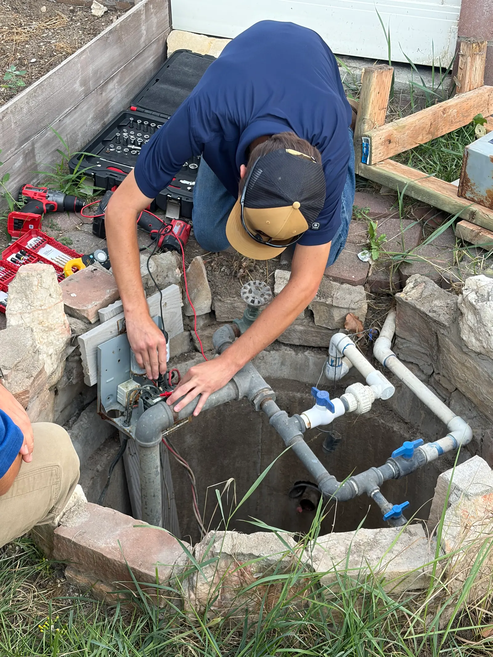 A Pure Irrigation technician testing an irrigation valve box with a multimeter during a repair